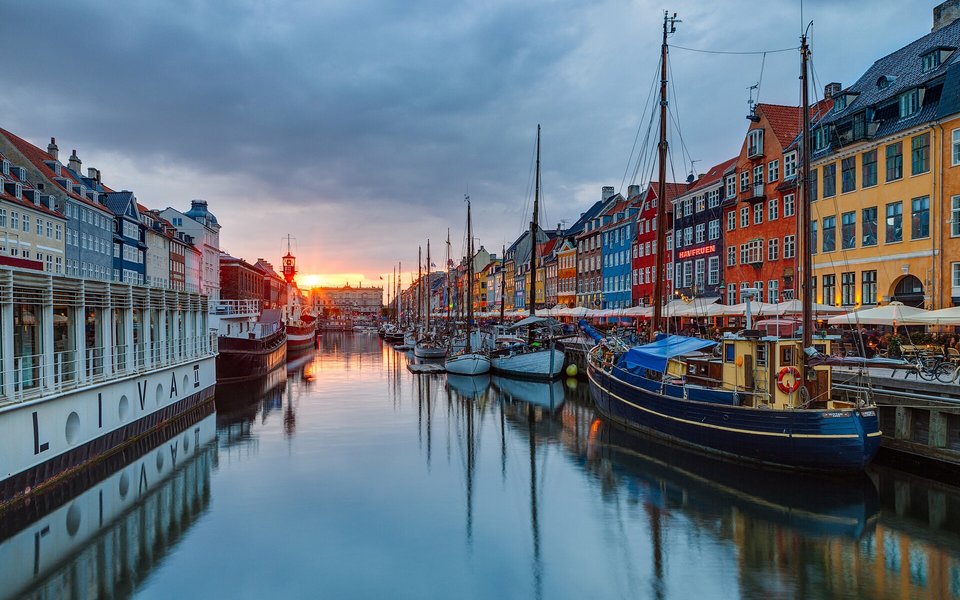Nyhavn canal in Copenhagen lined with colorful townhouses and sailboats at sunset