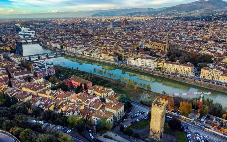 Aerial view of Florence with the Arno River, Duomo dome and terracotta rooftops under a clear sky