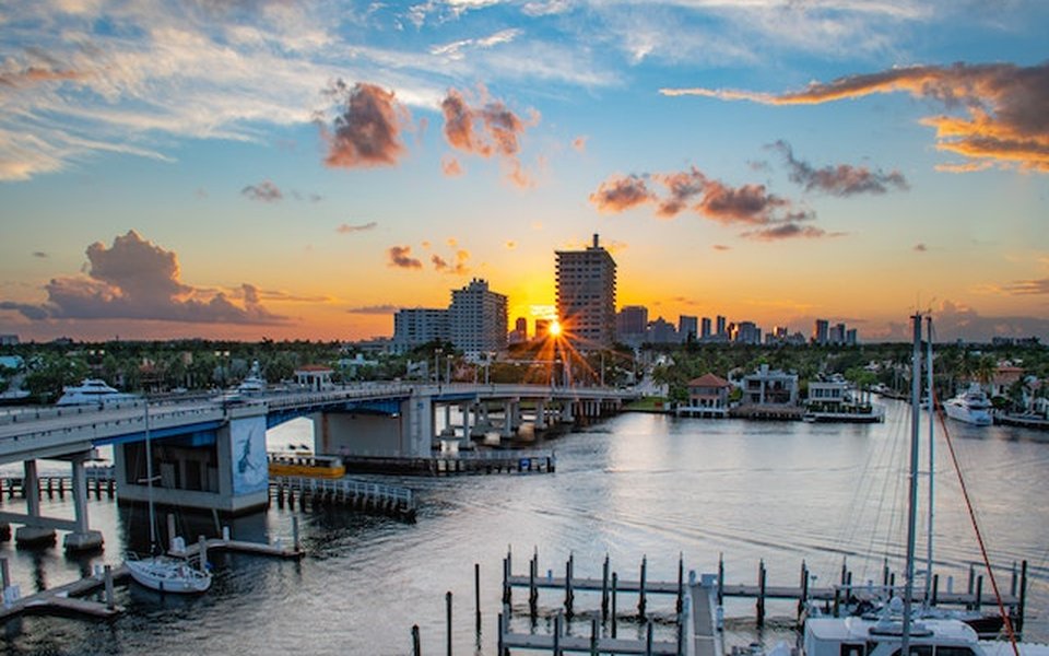 Sunset over a Florida waterway with a drawbridge, marina docks and a coastal skyline