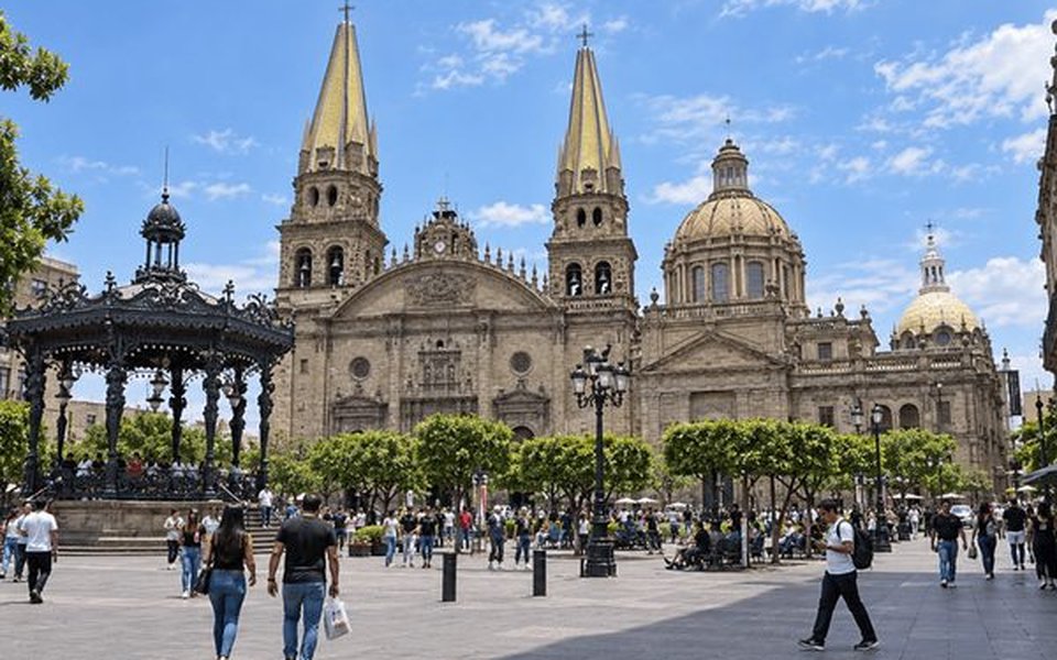Guadalajara Cathedral with yellow-tiled twin spires and dome across Plaza de Armas and its wrought-iron gazebo