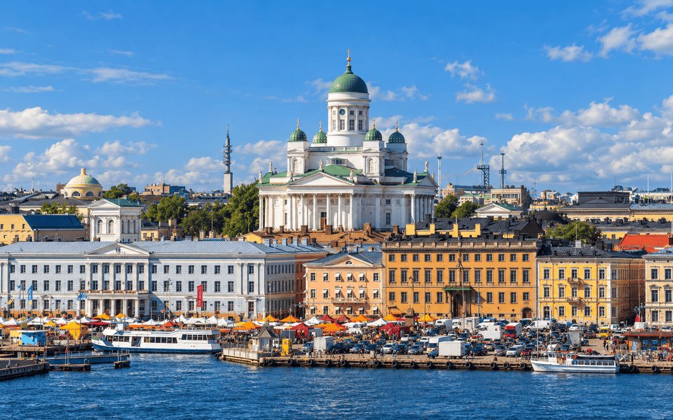 Helsinki Cathedral with green domes rising above colourful harbour-front buildings and orange market tents at South Harbour