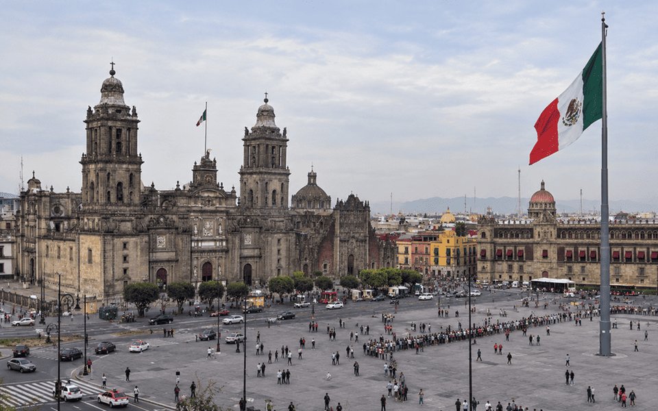 Mexico City Zócalo with the Metropolitan Cathedral, National Palace and a large Mexican flag under an overcast sky