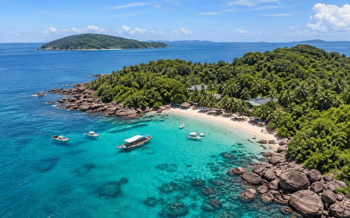 Turquoise cove with white sand beach, boats and jungle hills on Phu Quoc, Vietnam