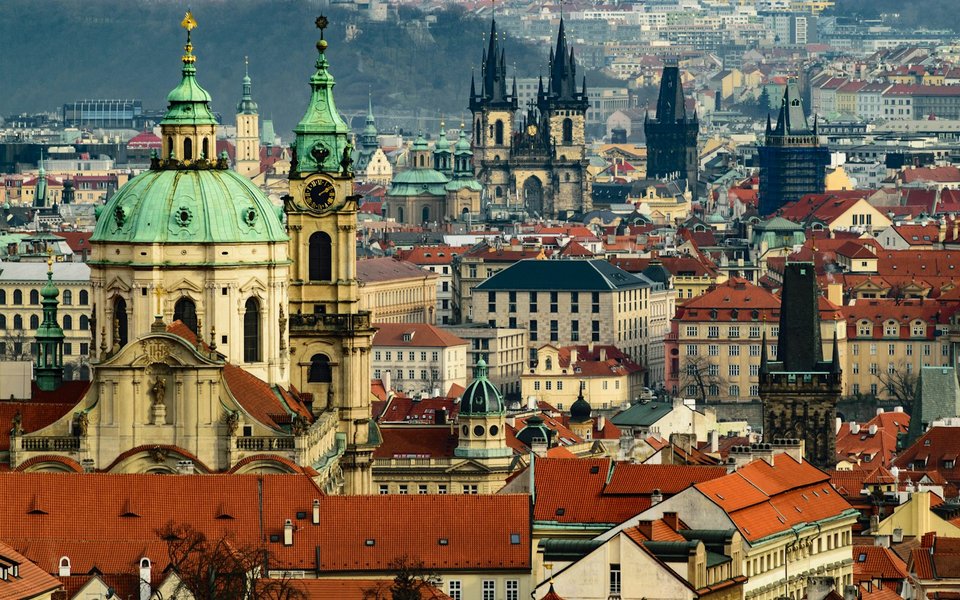 Prague rooftops with the green dome of St. Nicholas Church and the twin Gothic spires of the Church of Our Lady before Týn