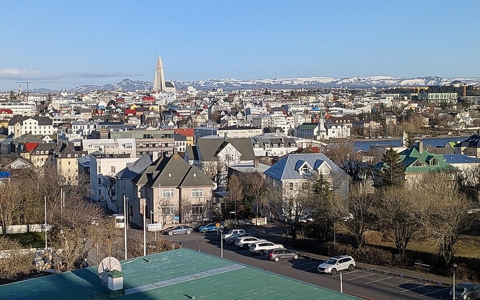 Elevated view of Reykjavik with Hallgrímskirkja church spire, colourful rooftops and snow-capped mountains under a clear blue sky