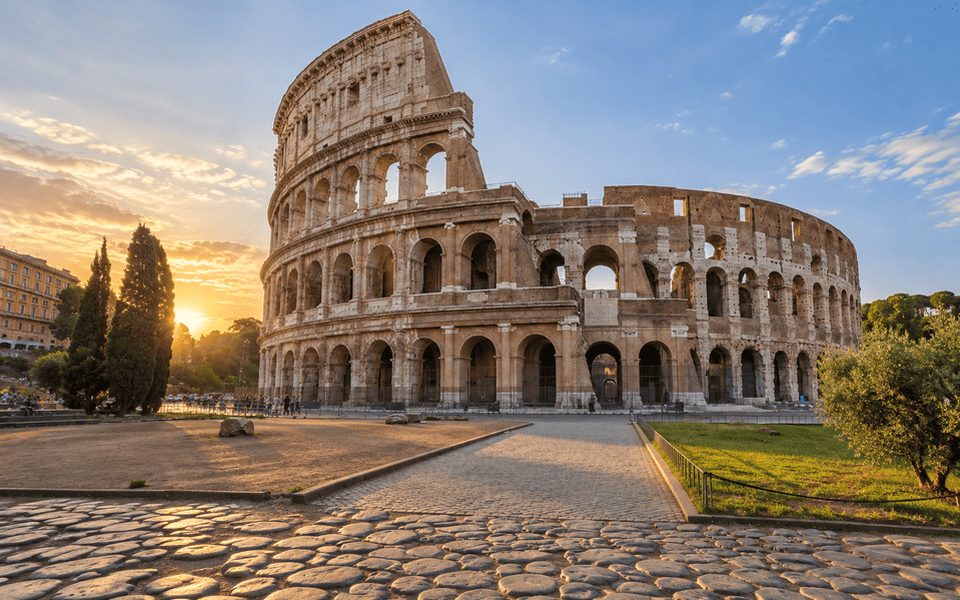 The Colosseum in Rome at golden hour with a cobblestone path in the foreground