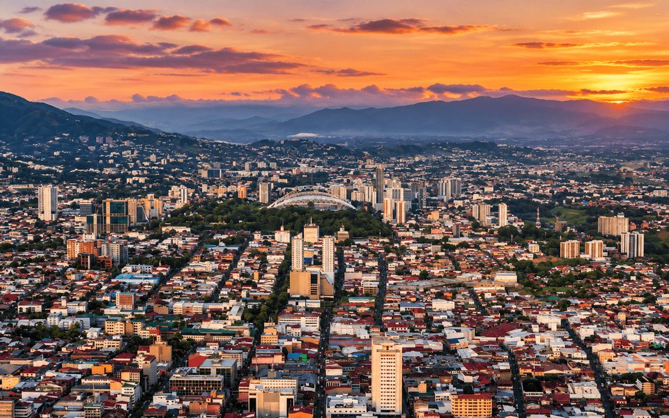 Sunset over San José, Costa Rica, with the National Stadium in La Sabana Park and mountains along the horizon