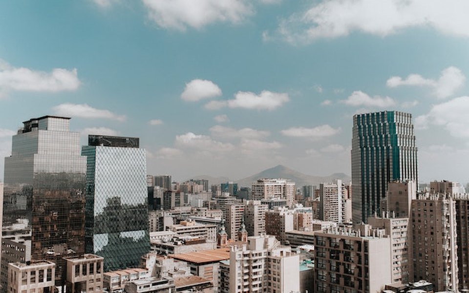 Santiago skyline with modern glass towers and mountains under a partly cloudy sky