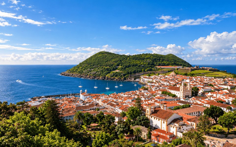 Sailboats docked in the marina at Angra do Heroísmo on Terceira in the Azores with green hills beyond